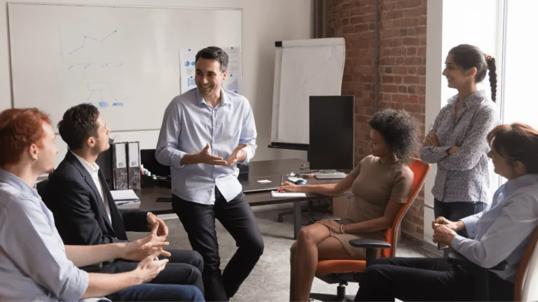 People gathered in a circle at an office listening to one person present.
