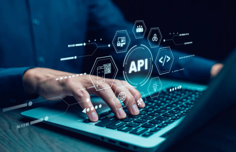 Blue glowing API interface with hexagonal icons hovering above a laptop keyboard, conveying a digital API concept