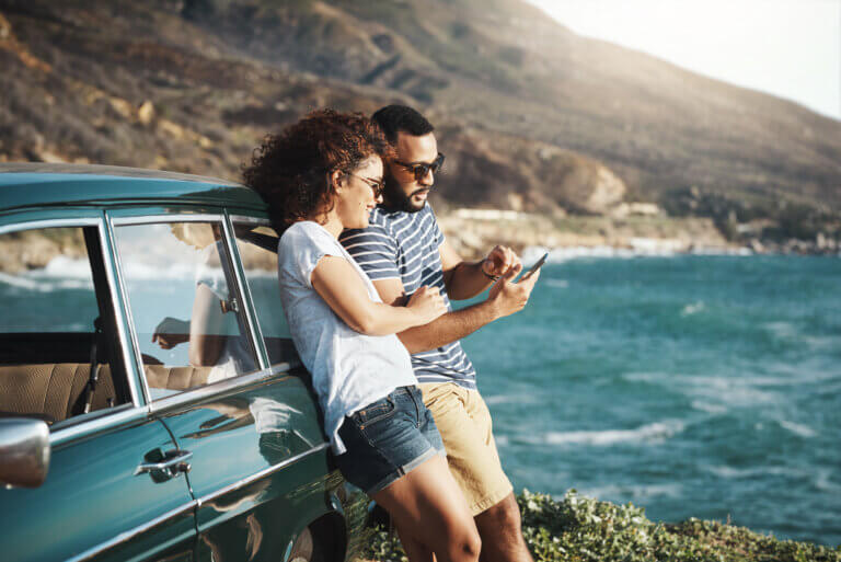 Couple enjoying a scenic view by the sea with a vintage car
